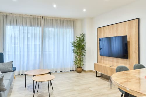 Sala de estar moderna en apartamento Tr3sor 22, Calella, con TV pantalla plana, mueble de entretenimiento en madera y comedor