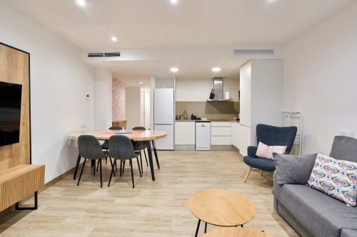 Moderno apartamento diáfano en Tr3sor Homes de Calella con cocina, comedor y sala con muebles de madera