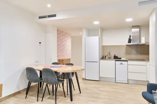 Cocina y comedor moderno en Tr3sor 22, apartamento de 2 dormitorios en Calella con electrodomésticos blancos y mesa de madera