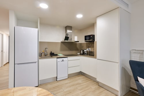 Cocina moderna en Tr3sor Homes, Calella, con muebles blancos, electrodomésticos de acero inoxidable y pisos de madera