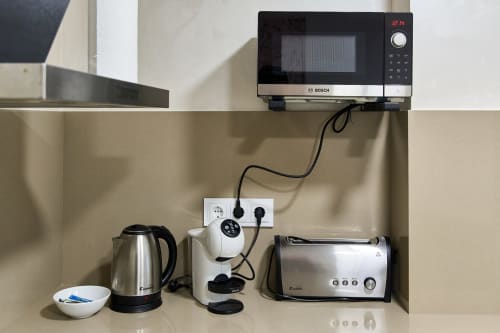 Kitchenette en Tr3sor Homes Calella: microondas, hervidor, tostadora y cafetera en la encimera