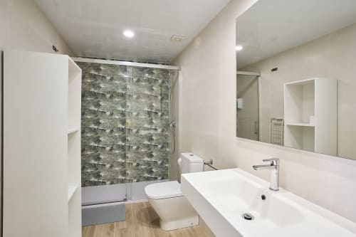 Baño moderno en Tr3sor Homes, Calella con lavabo blanco, inodoro, mampara de ducha estampada y espejo