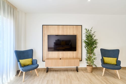 Sala de estar moderna en Tr3sor Homes de Calella con sillas azules, mueble para TV de madera y planta decorativa