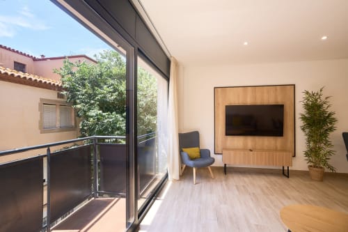 Moderno salón en apartamento Tr3sor Homes Calella con TV, cómodos asientos y acceso a balcón
