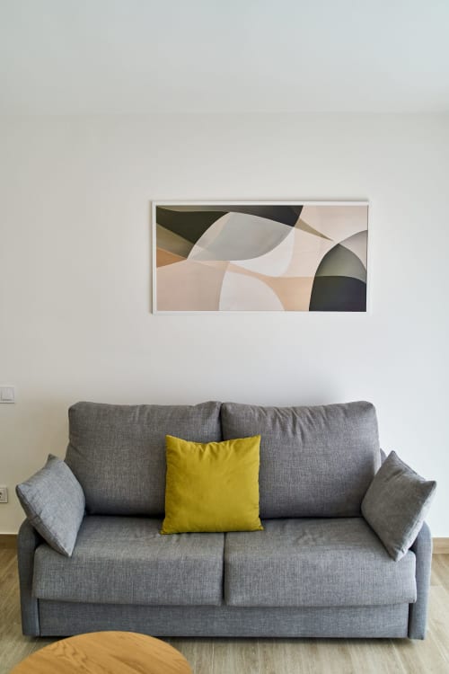 Sala de estar moderna en apartamento Tr3sor 23, Calella con sofá gris, cojín amarillo y arte abstracto en la pared