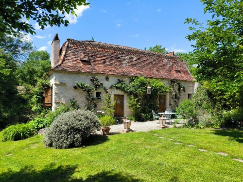 Rustic stone cottage at Les 2 Brigards B&B in Monestier, France, surrounded by lush gardens and greenery