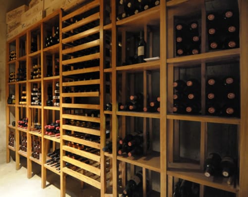 Bodega de almacenamiento de vinos con estanterías de madera y vitrinas en Restaurant Hostal Grau, Tarragona