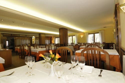 Comedor del Restaurante Hostal Grau en Tarragona con sillas de madera, manteles blancos e iluminación cálida