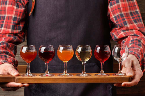 Personne tenant un vol de verres à vin en bois au Domaine des Oiseaux de Passage, Escolives-Sainte-Camille