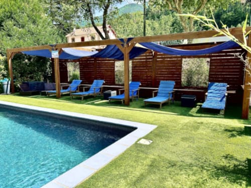 Pool and blue lounge chairs under pergola at Hôtel les Alizés, Puget-Théniers