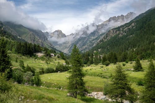 Vallée alpine avec prés verdoyants, forêt de conifères et montagnes brumeuses près de Puget-Théniers