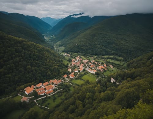 Vue aérienne de l'Hôtel les Alizés niché dans la vallée de Puget-Théniers, entouré de montagnes boisées et de bâtiments aux toits rouges