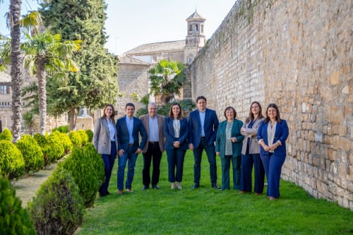 Hotel staff team standing on lawn at Alojamientos Estrella Baeza in historic Baeza, Spain with stone walls and church tower