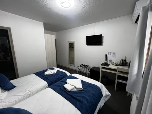 Modern double bedroom at Hôtel les Alizés in Puget-Théniers with blue bedding, flat-screen TV, and work desk