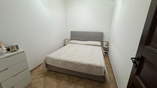 Camera da letto nell'appartamento Solunto Home Holiday con letto matrimoniale, testata grigia, cassettone bianco e pavimento in legno a Santa Flavia