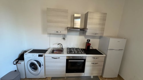 Cucina compatta dell'appartamento Solunto Home Holiday con lavatrice, fornello a gas, forno e frigorifero