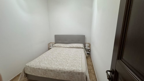 Camera minimalista presso Solunto Home Holiday a Santa Flavia con letto singolo, testata grigia e pareti bianche