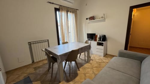 Soggiorno dell'appartamento Solunto Home con tavolo da pranzo, divano, TV e accesso al balcone a Santa Flavia