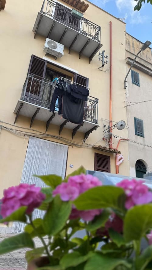 Balcone dell'appartamento vacanze Solunto Home a Santa Flavia con fiori rosa e vista sulla città