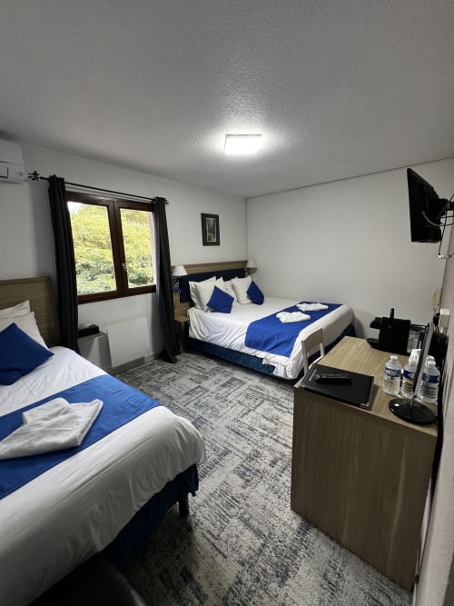 Camera tripla con due letti e bagno privato all'Hôtel les Alizés a Puget-Théniers, con biancheria blu e arredamento moderno