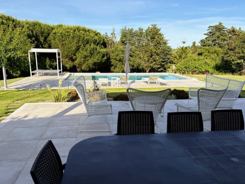 Pátio à beira da piscina da Quinta Vale da Paz com área de refeições, espreguiçadeiras e jardins bem cuidados em Azambuja