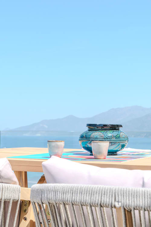 Beachfront dining setup at Villa Roya with turquoise decorative bowls overlooking Saint-Florent bay and mountains