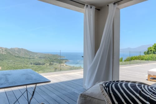 Terrasse Villa Roya à Saint-Florent avec vue sur la mer Méditerranée, espace détente aux coussins rayés