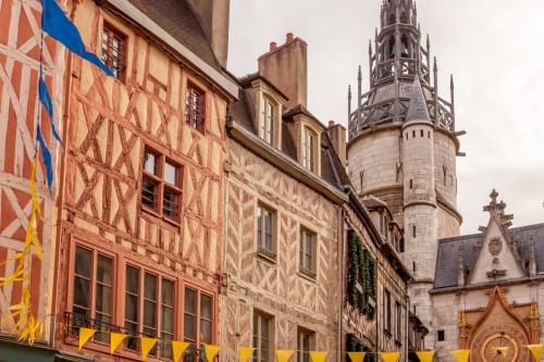Maisons à colombages médiévales décorées de guirlandes jaunes près d'une tour en pierre à Escolives-Sainte-Camille, France