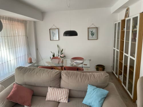 Sala de estar moderna en apartamento Algemesi Home Valencia con sofá beige, mesa de comedor de cristal, lámpara colgante y vistas a la ciudad