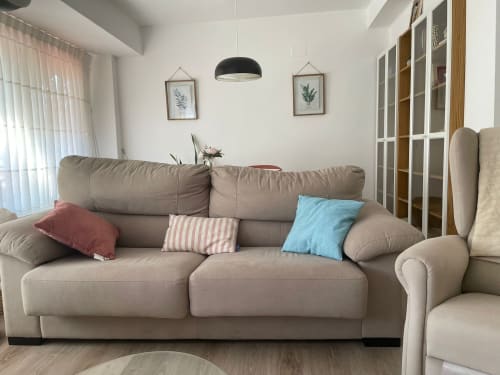 Sofá beige cómodo con cojines coloridos en la luminosa sala de estar de Algemesi Home, apartamento en Valencia