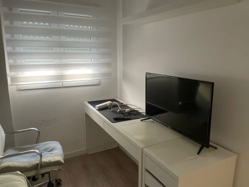 Dormitorio moderno con televisor de pantalla plana, escritorio blanco, estantería y silla en el apartamento Algemesi Home en Valencia, España