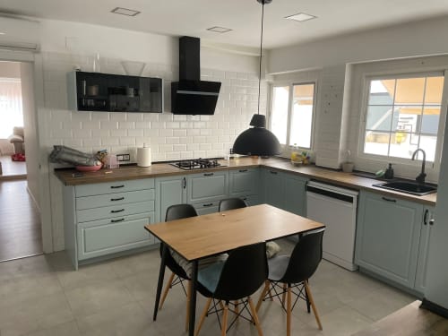Cocina moderna con gabinetes verde salvia, encimeras de madera, acentos negros y mesa de comedor en apartamento vacacional en Algemesi