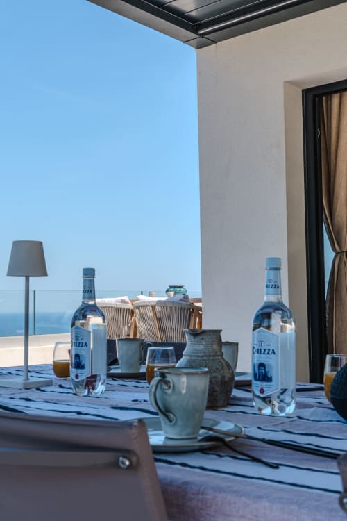 Terrasse face mer de la Villa Roya à Saint-Florent avec vue sur la Méditerranée, bouteilles d'eau et décoration méditerranéenne