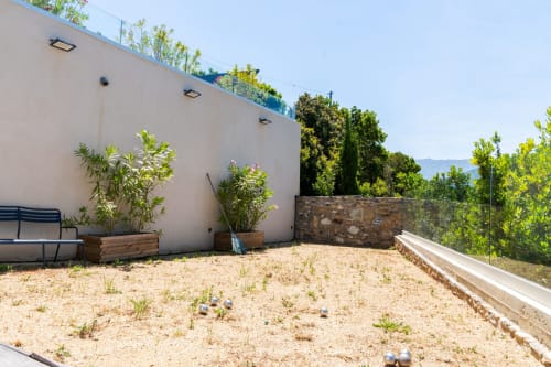 Terrasse sur le toit de la Villa Roya à Saint-Florent avec plantes en pot, transats et vue sur les montagnes