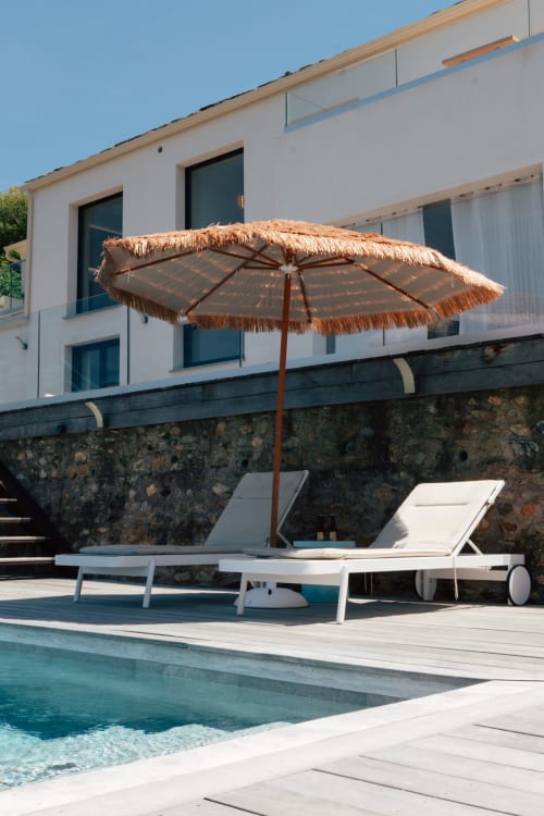 Parasol en paille et transats blancs au bord de la piscine de la Villa Roya, Saint-Florent
