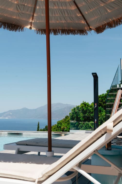 Terrasse piscine de la Villa Roya avec parasol tressé dominant la baie de Saint-Florent et les montagnes