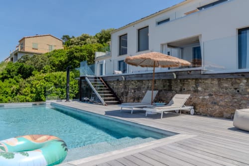 Terrasse piscine de la Villa Roya avec transats, parasol et bâtiment blanc moderne à Saint-Florent