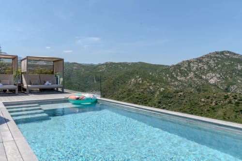 Piscine à débordement de la Villa Roya surplombant les montagnes verdoyantes de Saint-Florent en Corse avec espace détente