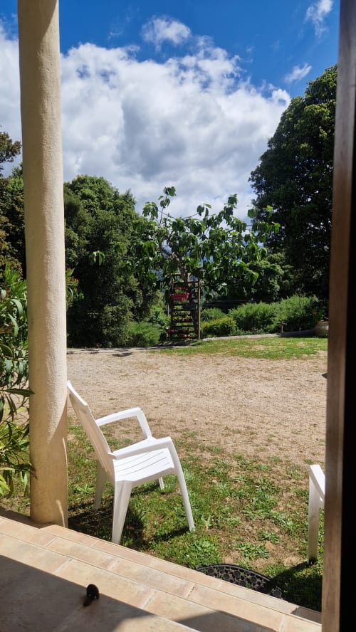 Chaise blanche sur la terrasse avec vue sur le jardin à Mare e Monti Vico, montagne verdoyante en arrière-plan