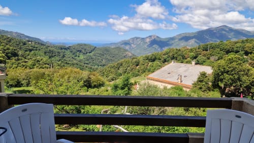 Balcon de Mare e Monti Vico avec chaises Adirondack blanches dominant les montagnes verdoyantes et les vallées vertes de Vico, Corse