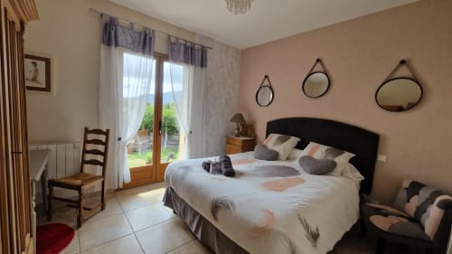 Chambre lumineuse à Mare e Monti Vico avec vue sur jardin, tête de lit noire, miroirs et portes donnant sur terrasse à Vico, FR