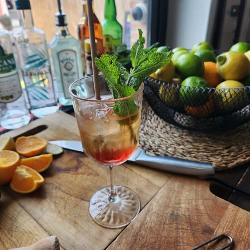 Cocktail garni de menthe au bar du BDM Hotel, Montastruc-la-Conseillère, avec agrumes frais et bouteilles de spiritueux