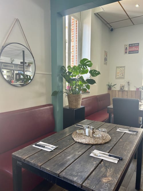 Alcôve moderne de l'hôtel BDM à Montastruc-la-Conseillère avec banquette bordeaux, table en bois foncé et monstera en pot