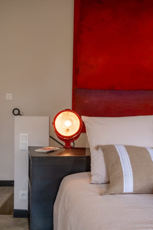 Chambre moderne au Jardin Secret avec tête de lit rouge, linge beige et lampe de bureau rouge illuminée