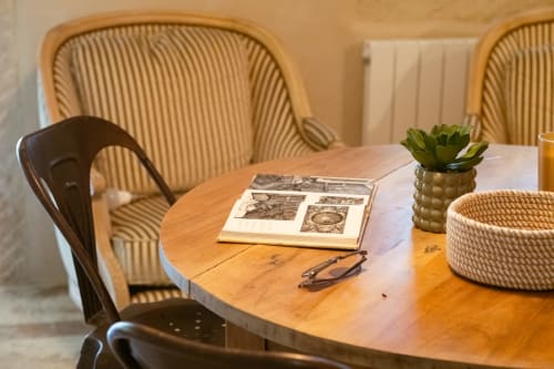 Élégant espace de travail à Le Jardin Secret à Grignan avec table ronde en bois, chaise noire et détails en rotin