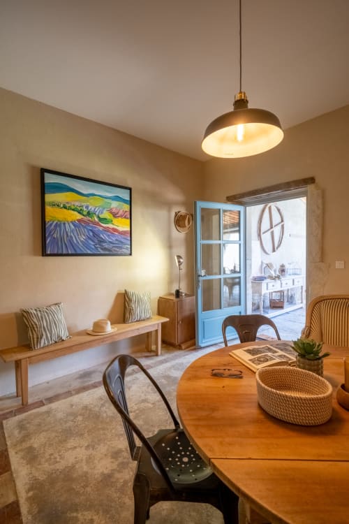 Salon chaleureux de la Suite l'Olivier au Jardin Secret à Grignan, avec table en bois, luminaire suspendu et œuvre d'art