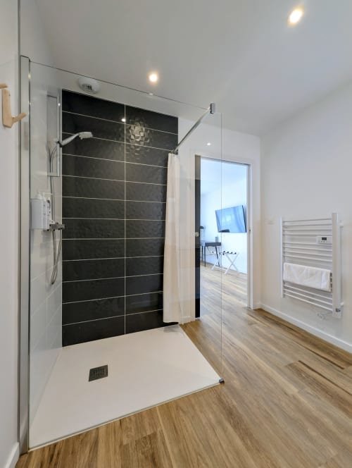 Salle de bain moderne avec douche à l'italienne, carrelage noir et paroi en verre à La Clairière aux Chênes, Treillières