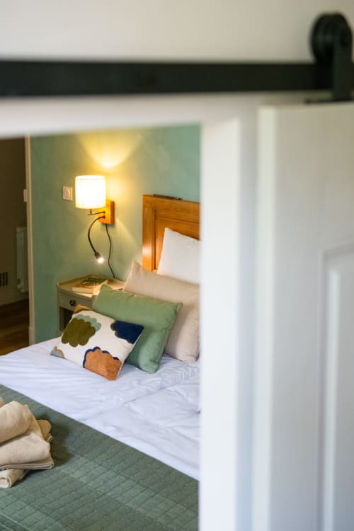Chambre accueillante au Jardin Secret à Grignan avec murs menthe, tête de lit en bois et lampe de chevet chaleureuse