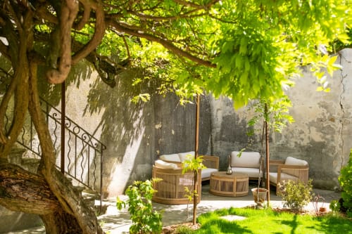 Cour ombragée au Jardin Secret de Grignan avec sièges en bois et verdure luxuriante en surplomb