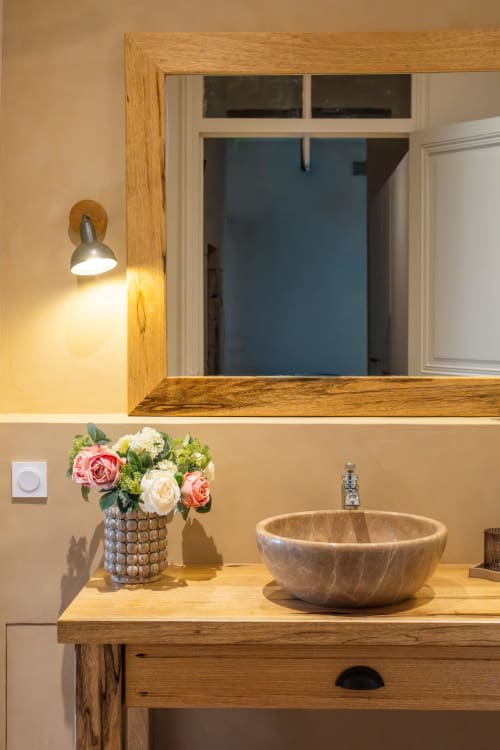 Vasque en pierre sur meuble de salle de bain en bois avec fleurs au Jardin Secret à Grignan
